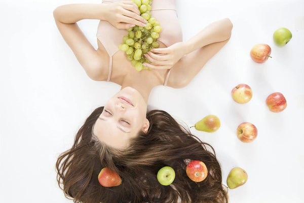 Donna con capelli castani circondata da mele