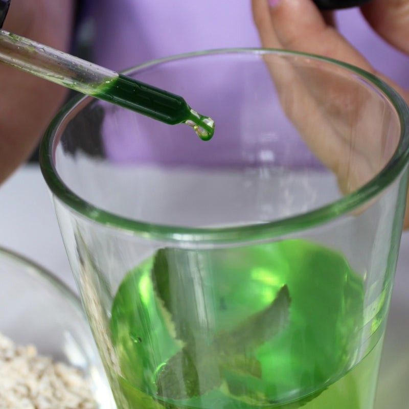 Visuel illustrant la prise de l'élixir Detox Drops avec une feuille de menthe dans le verre
